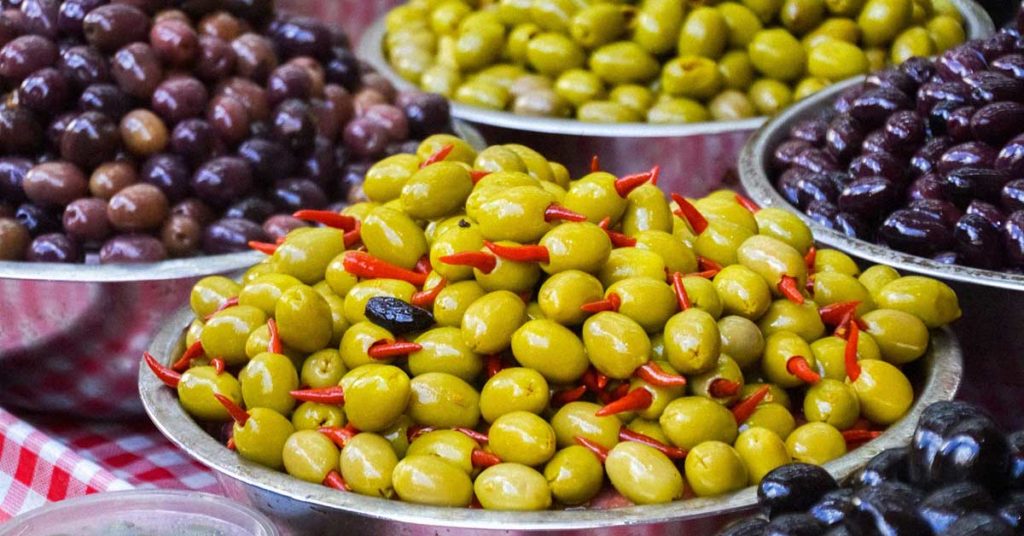 Verschiedene Arten von Oliven, in Schalen nebeneinander angerichtet. Diese können Ursache einer Olivenallergie sein.